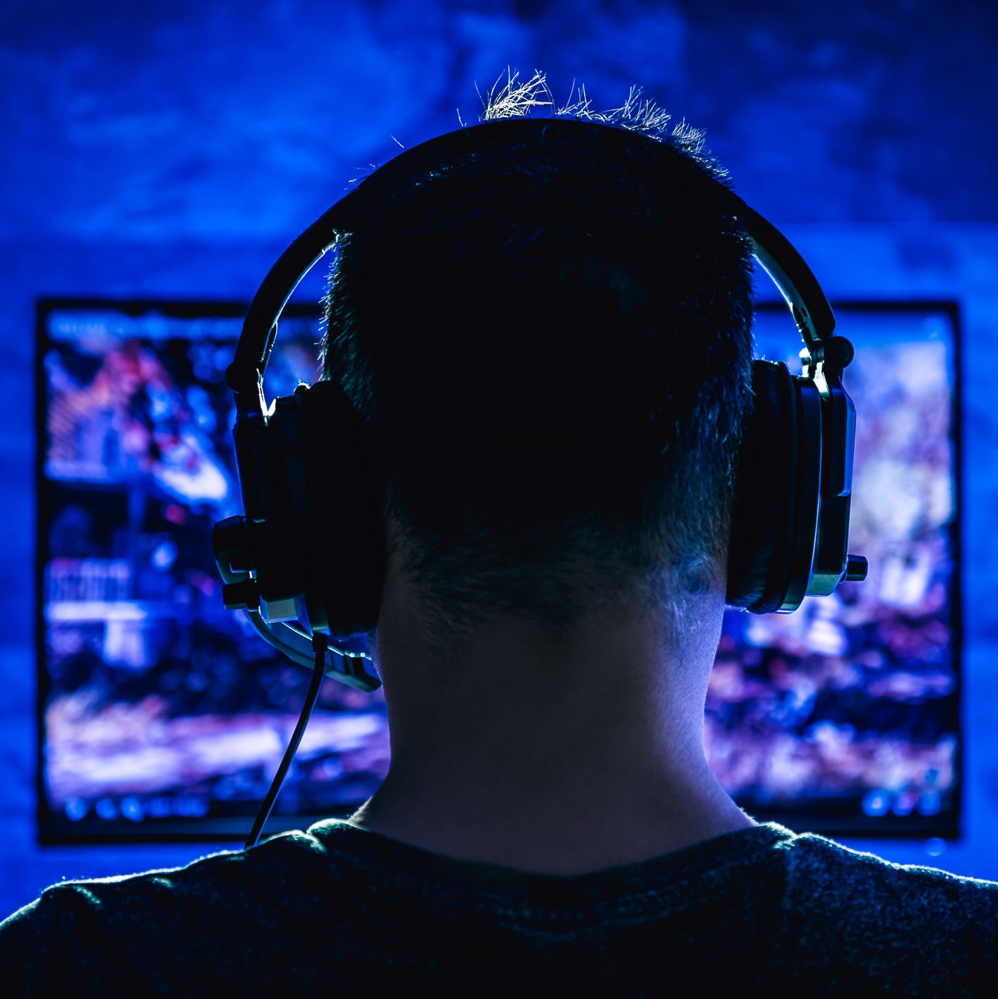 hinterkopf eines mannes mit headset vor einem pc bildschirm