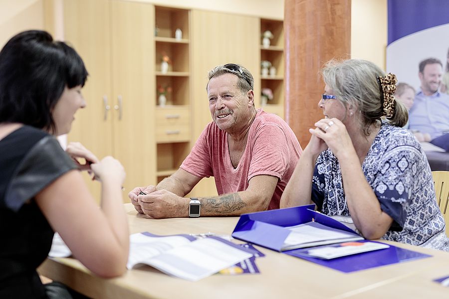 ein pärchen sitzt bei der bürgerstunde und spricht mit einer frau