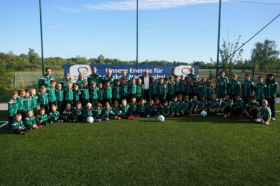 ein gruppenbild von vielen kindern in fußball trikots auf einer wiese