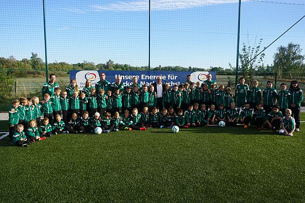 ein gruppenbild von vielen kindern in fußball trikots auf einer wiese