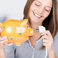 eine lächelnde frau hat ein sparschwein und ein kabel in der hand