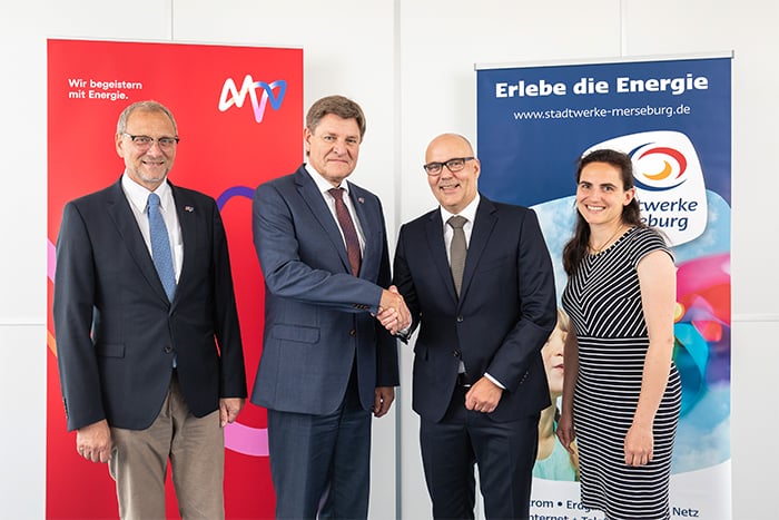 4 menschen vor einem banner reichen sich die hände