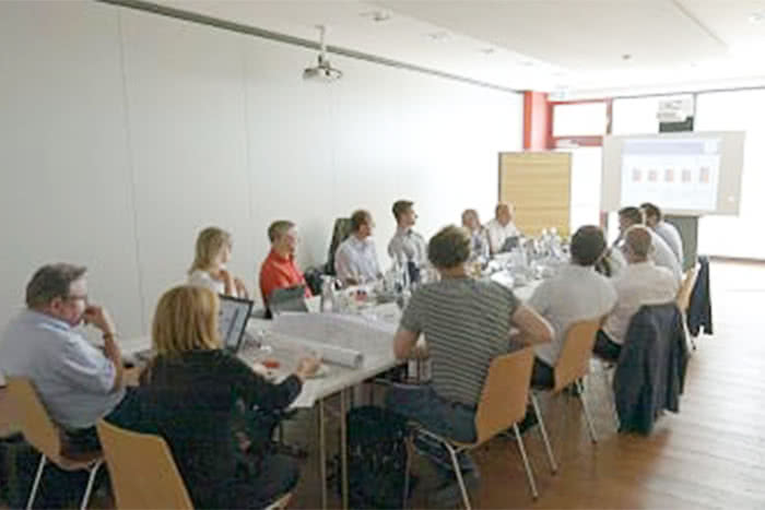 projektbesprechung zwischen einem dutzend menschen an einer tafel