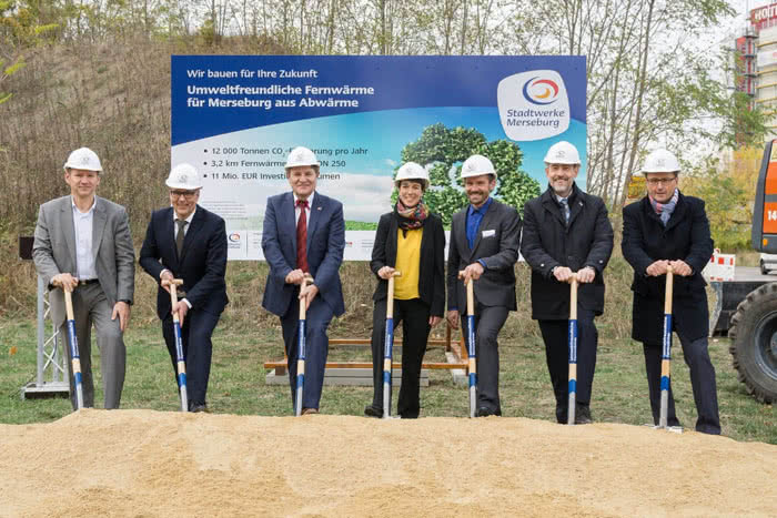 7 Personen begleiten einen spatenstich auf eine baustelle für ein foto