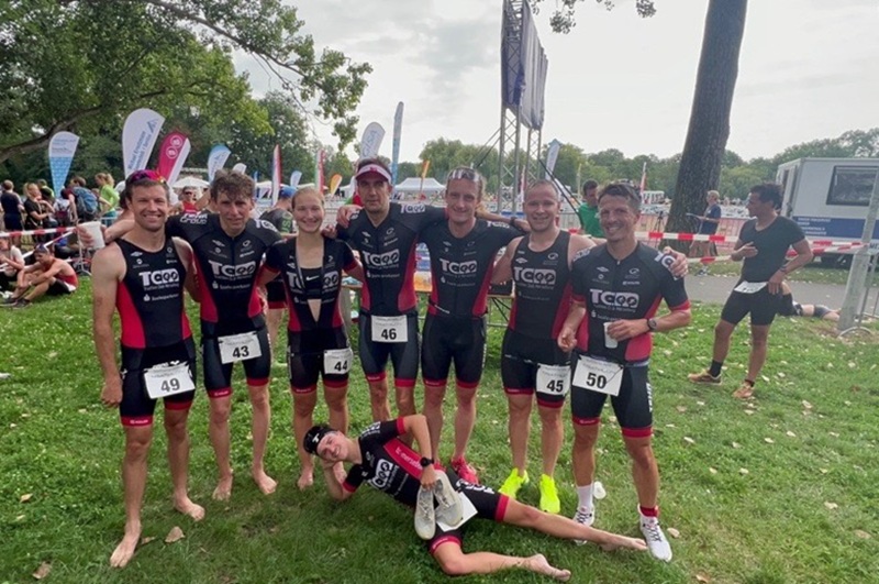 Das Bild zeigt eine Gruppe von acht Wettkampfteilnehmenden des Triathlon Club Merseburg e. V. auf einer Wiese.