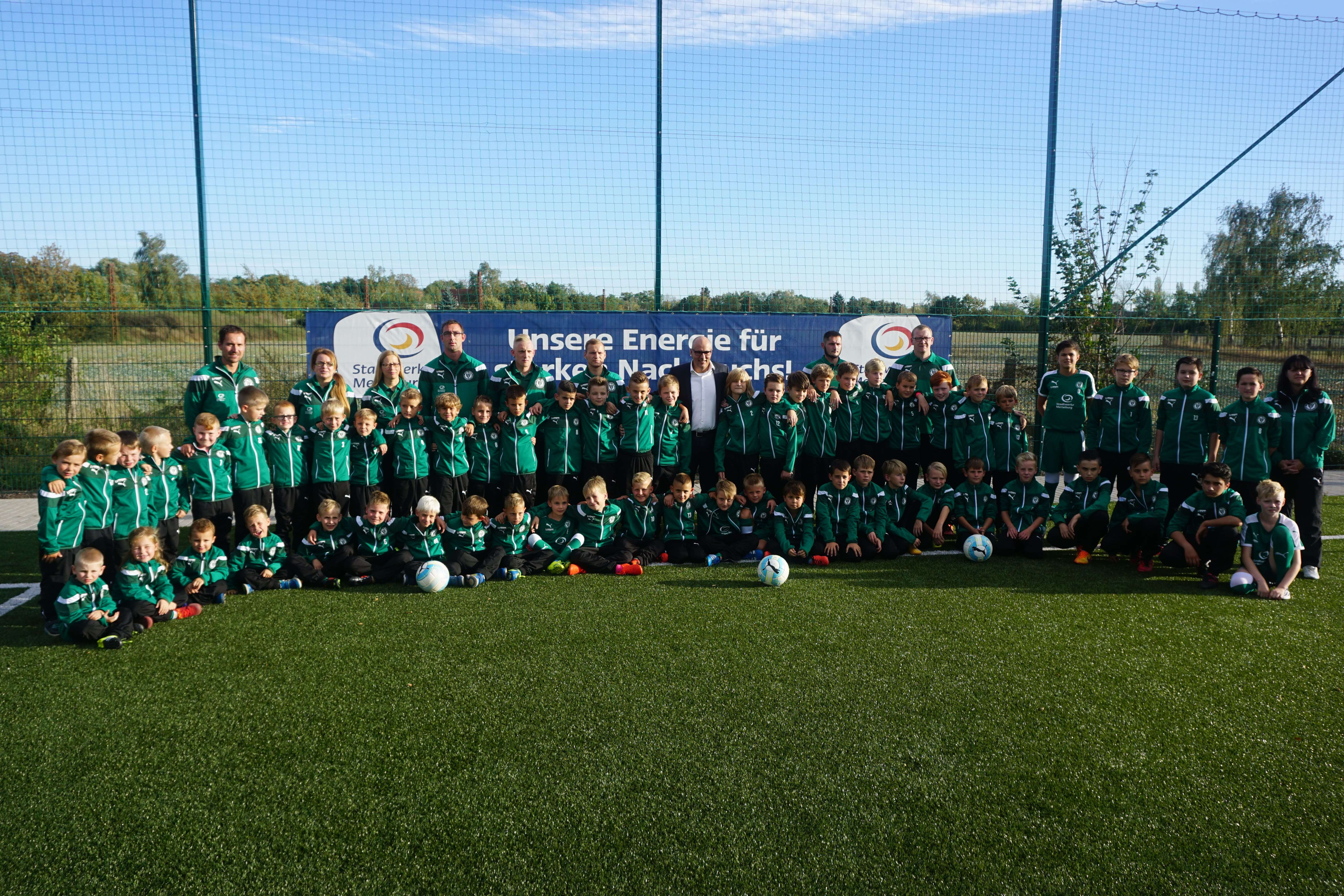 ein gruppenbild von vielen kindern in fußball trikots auf einer wiese